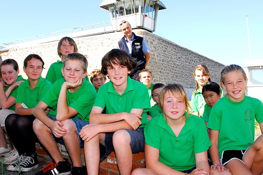 School students and tour guide posing in front of gun tower